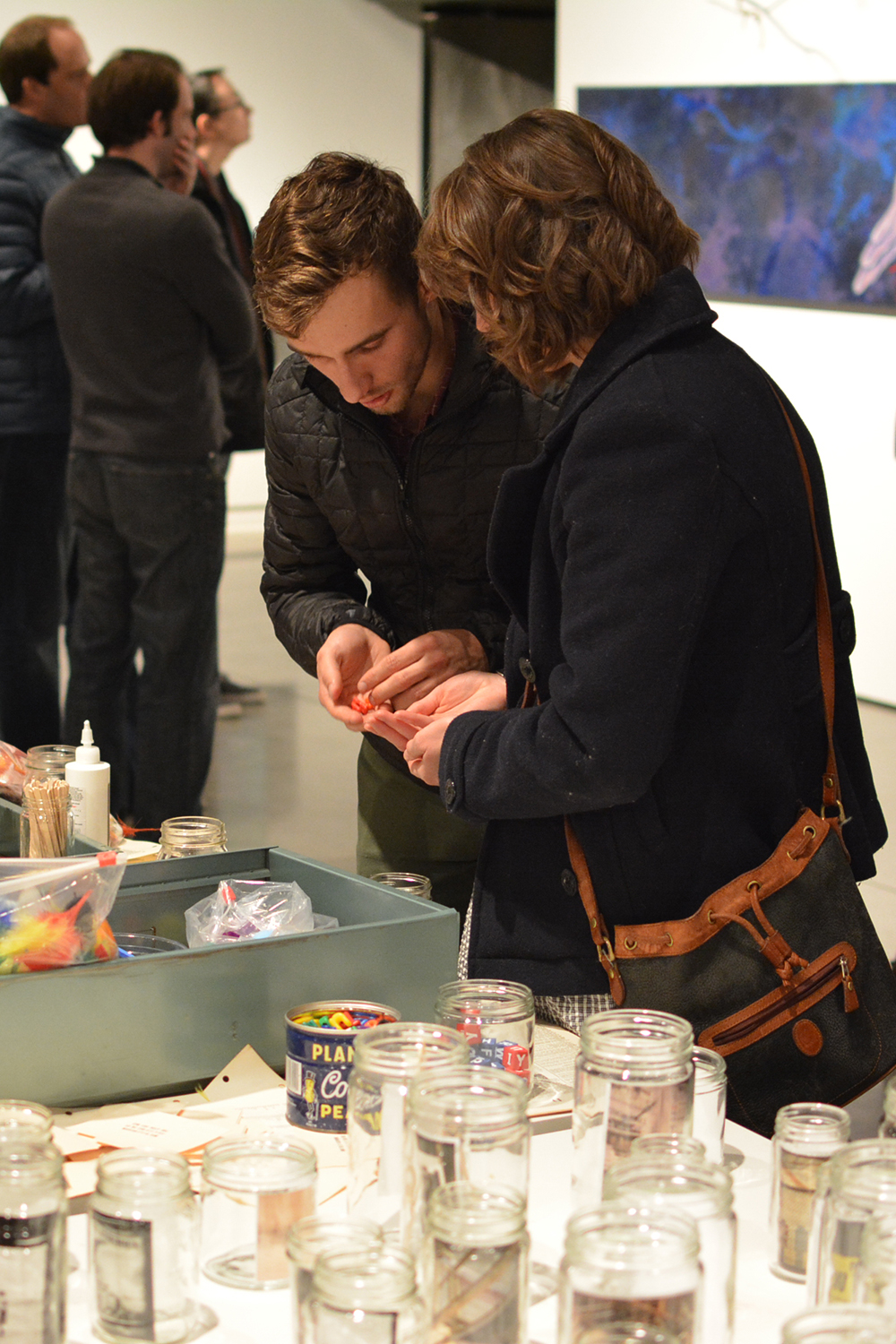 Visitors filling the jars with objects during the opening reception.